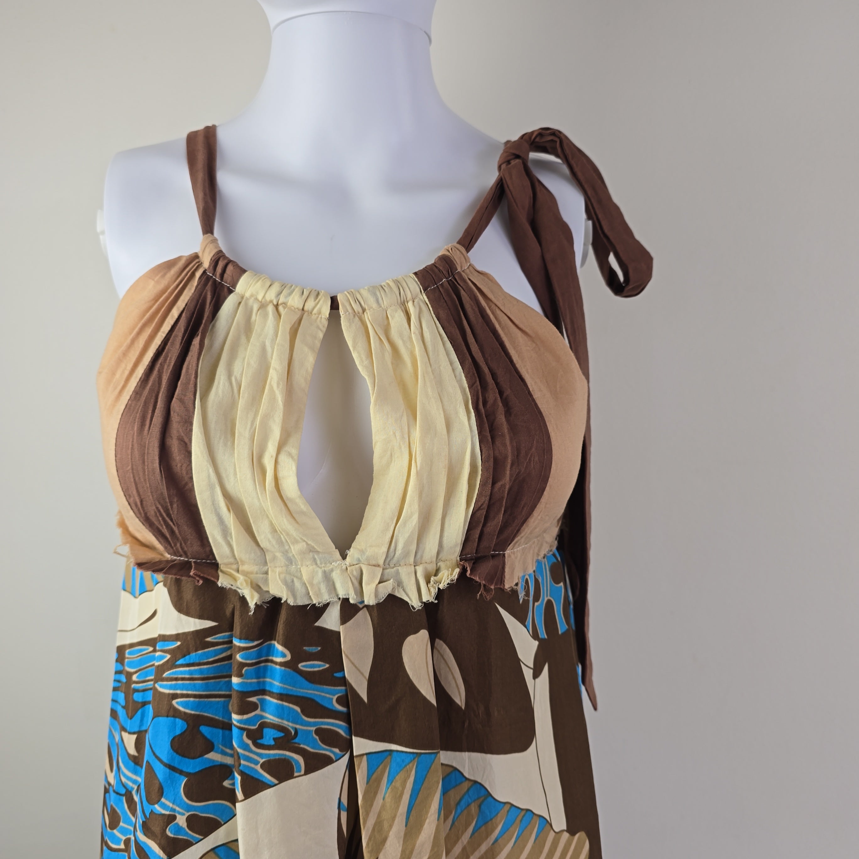 Mannequin wearing a brown and beige dress with abstract pattern on a neutral background