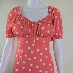 Mannequin wearing a coral dress with white polka dots on a plain background