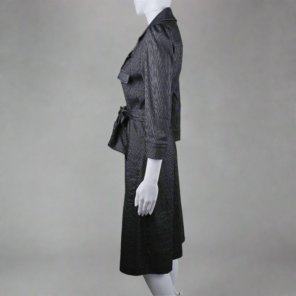 Mannequin wearing a black suit with white gloves on a neutral background