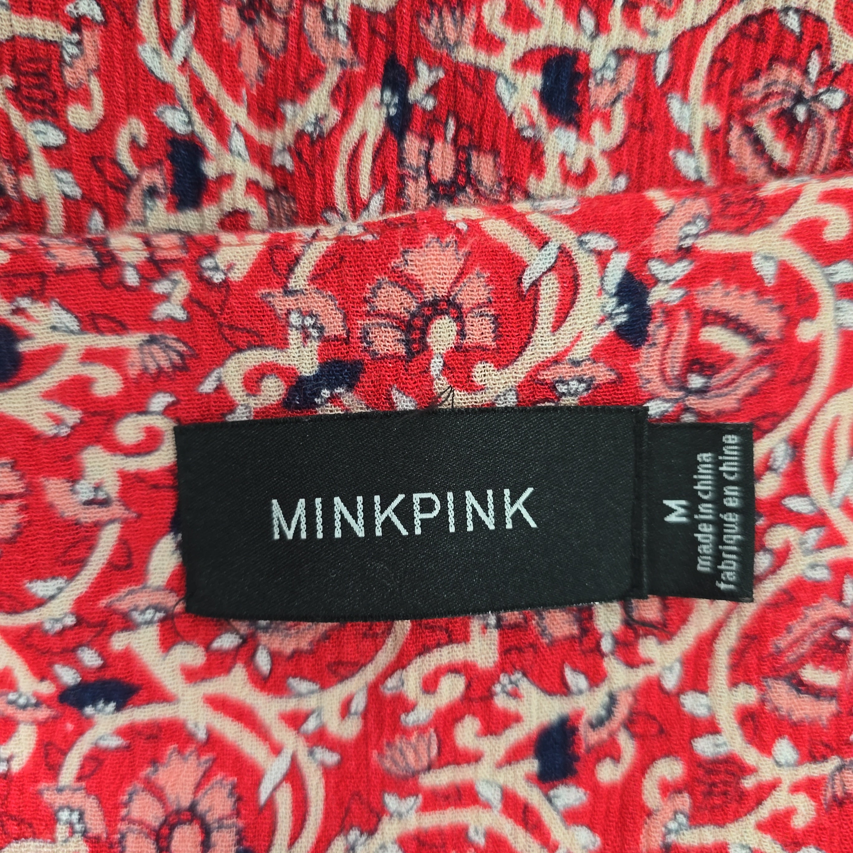 Minkpink label on a red patterned fabric background