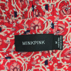 Minkpink label on a red patterned fabric background