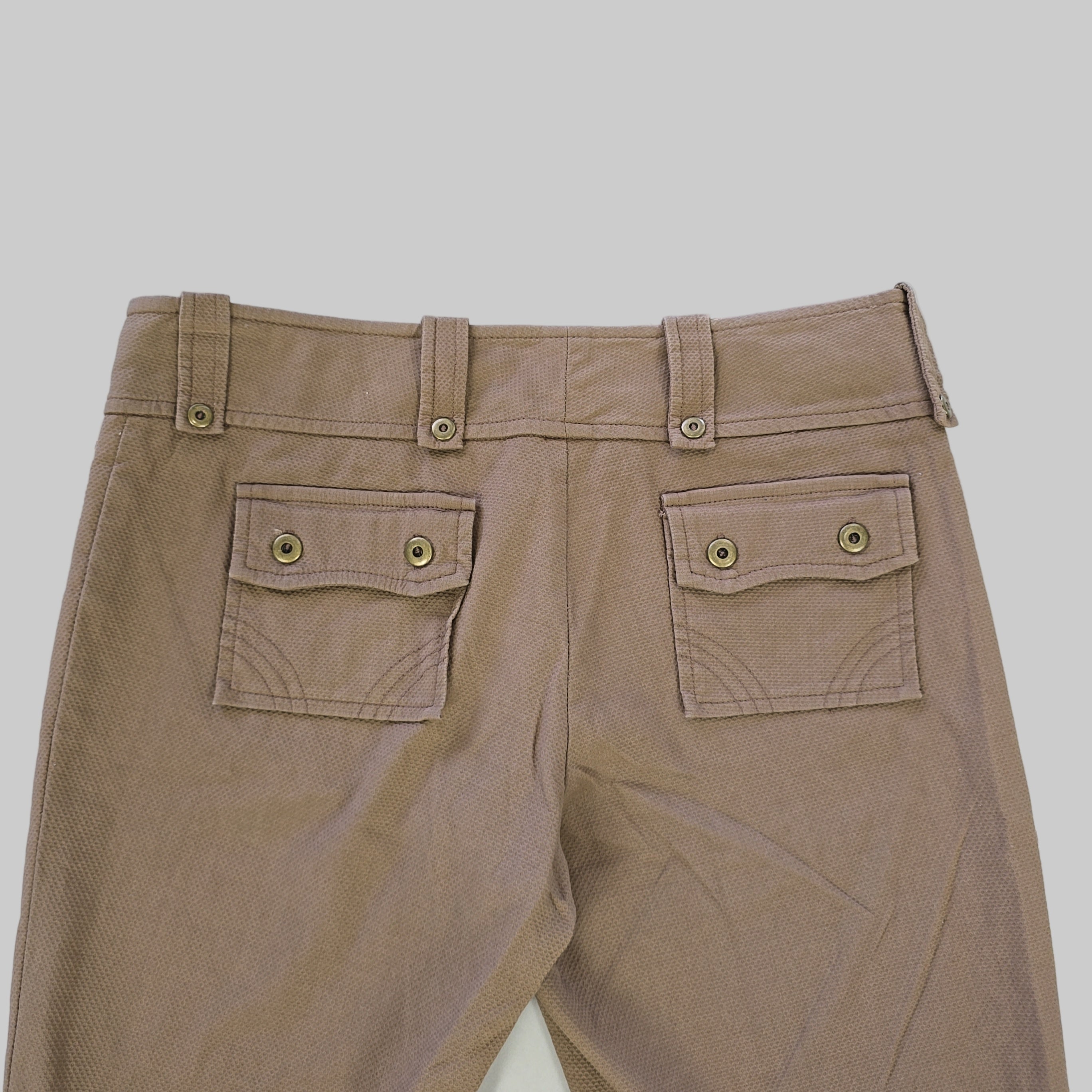 Close-up of brown pants with button details on a white background