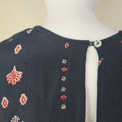Black garment with red floral patterns on a mannequin against a beige background