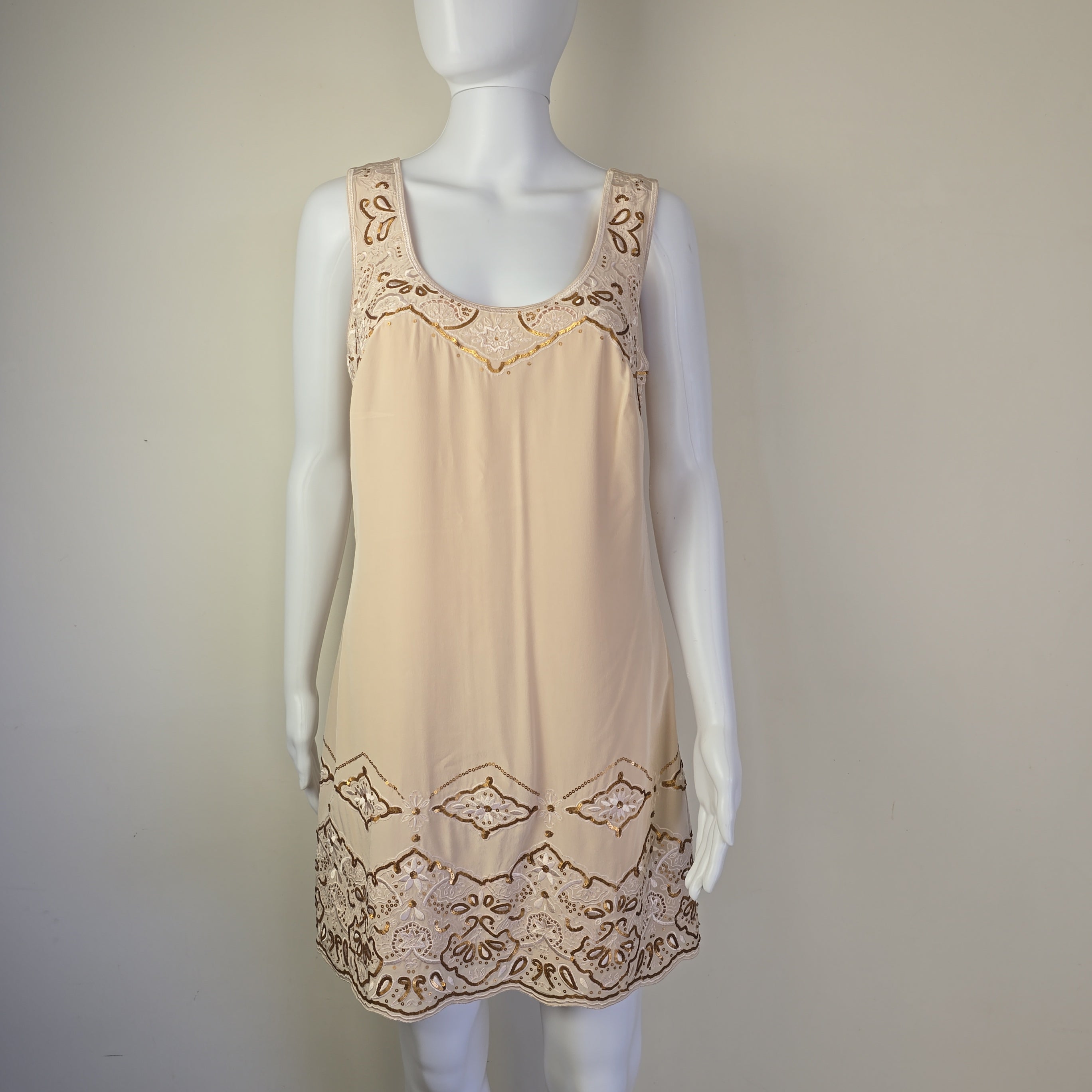 Beige dress with lace details on a mannequin against a plain background