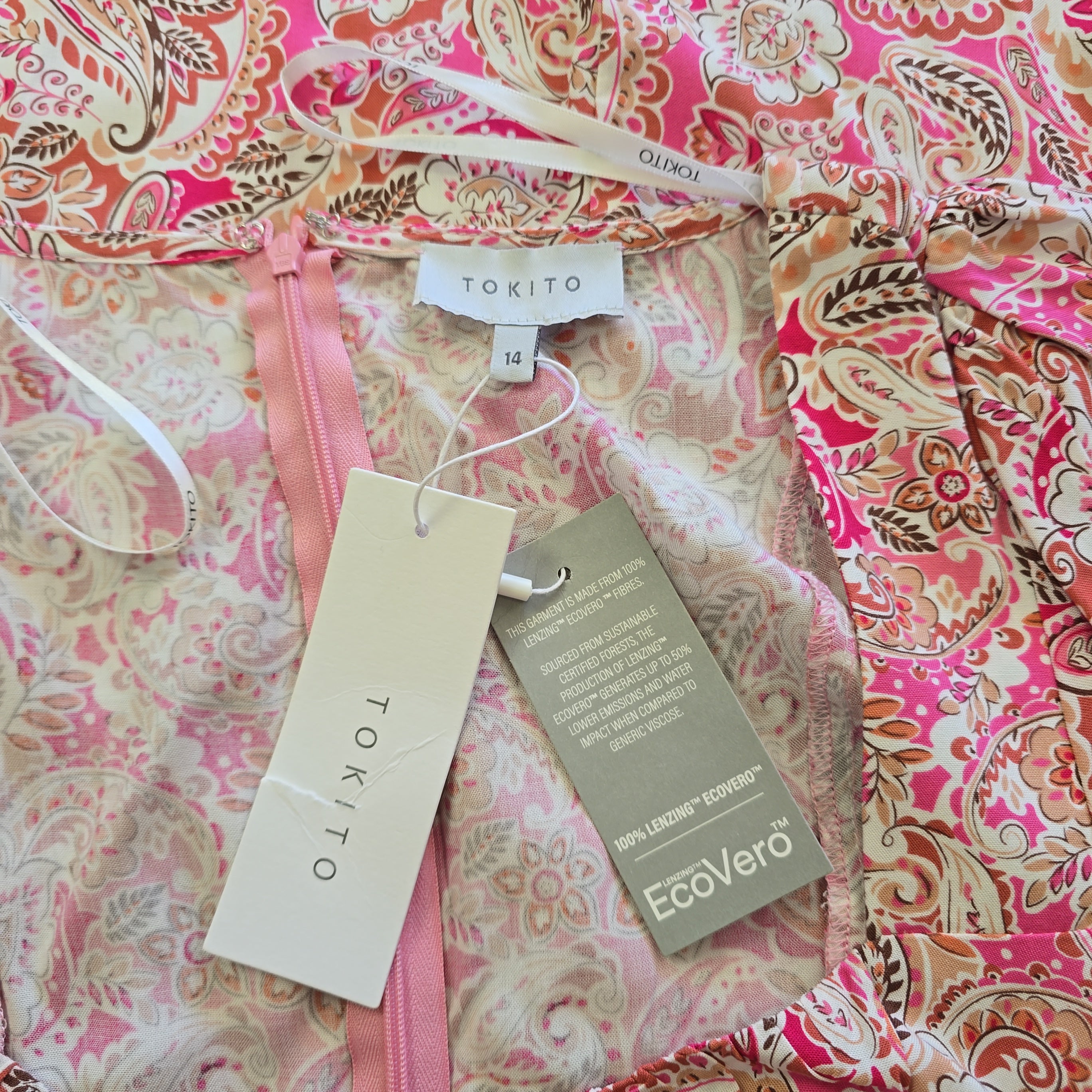 Pink and white patterned dress with visible brand tags on a pink and white floral background