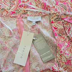 Pink and white patterned dress with visible brand tags on a pink and white floral background