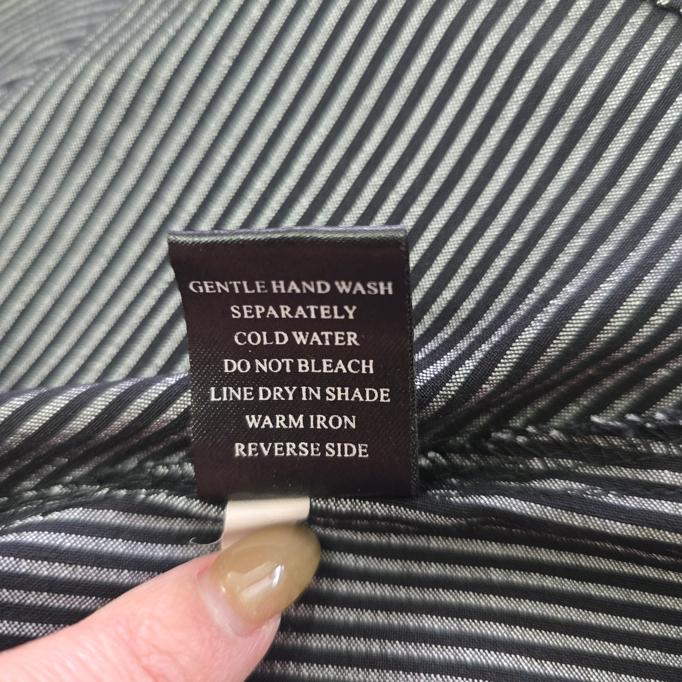 Fabric tag with care instructions on a striped fabric background