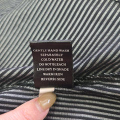 Fabric tag with care instructions on a striped fabric background