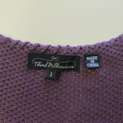 Close-up of a purple textured fabric with a label on a light background