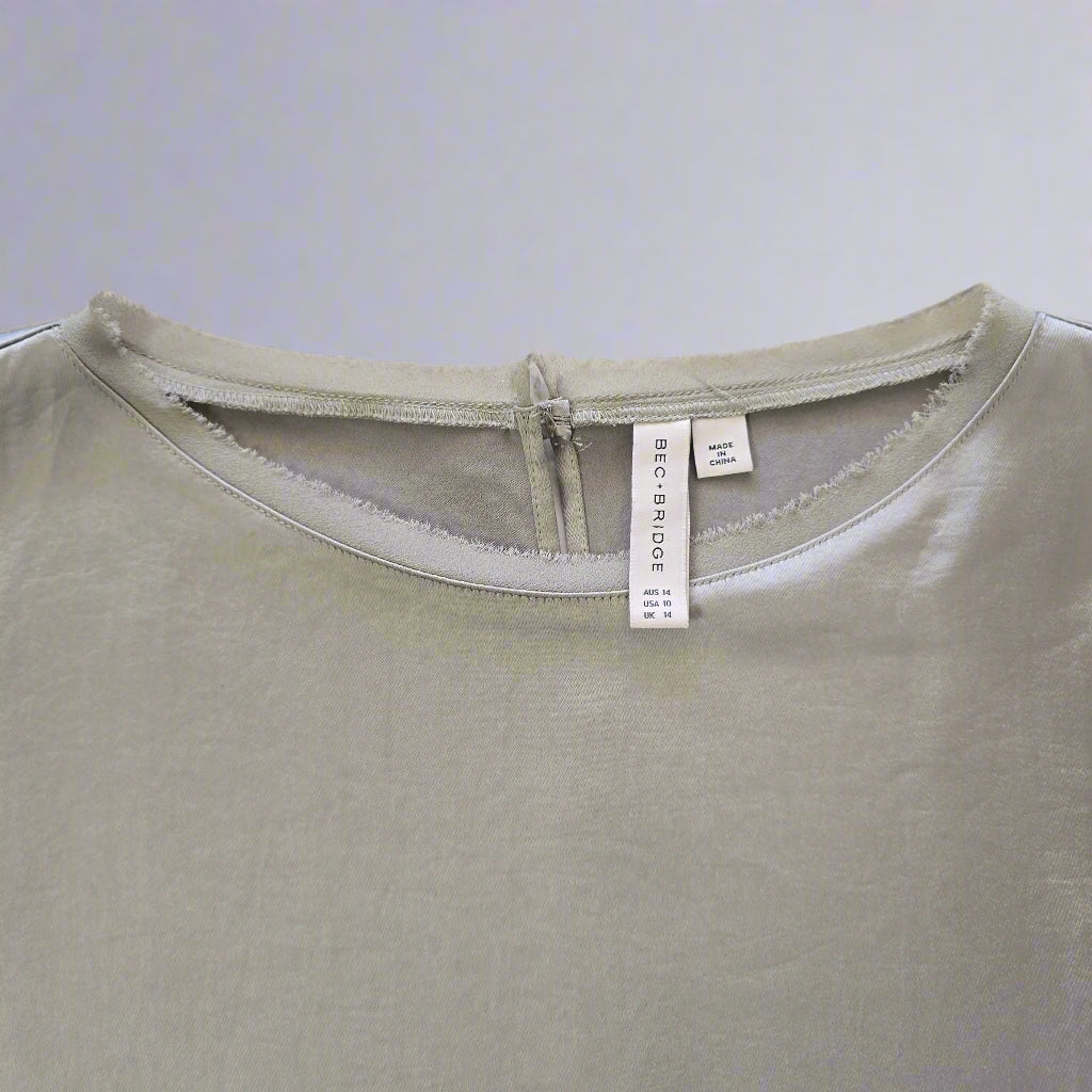 Close-up of a light green Dress with a brand label on a neutral background