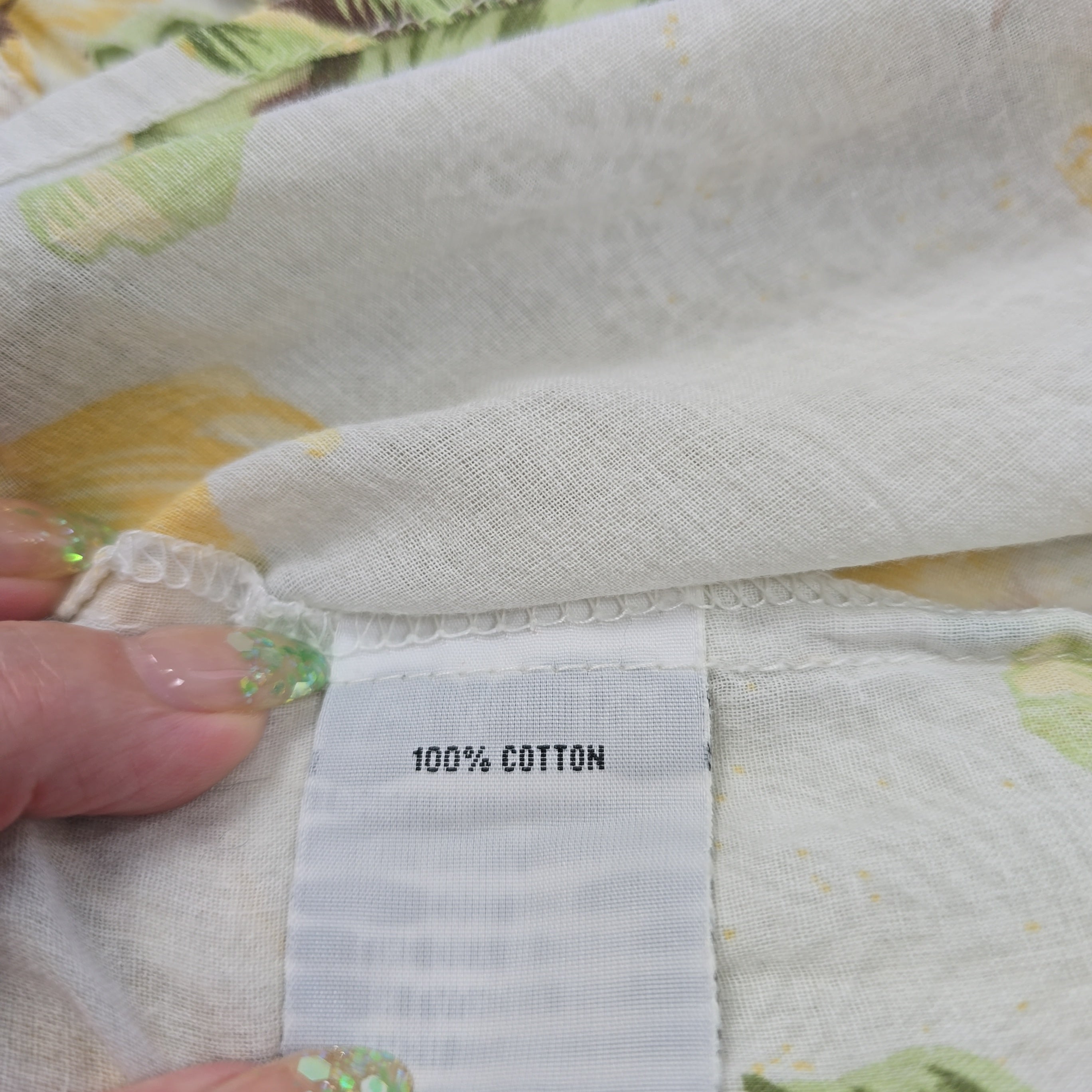 Close-up of a fabric with a '100% Cotton' label, held by a hand.