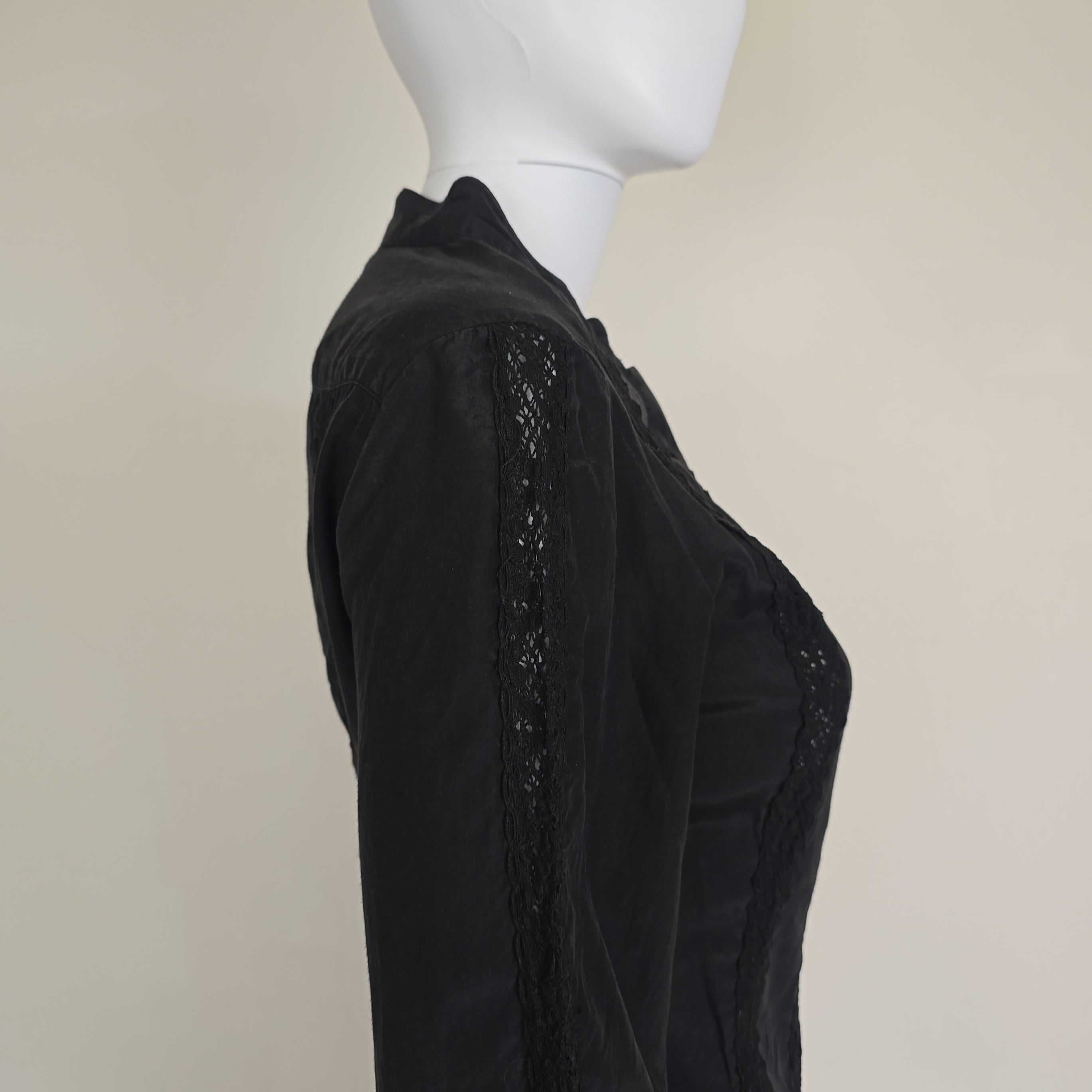 Black lace-trimmed garment on a mannequin against a beige background