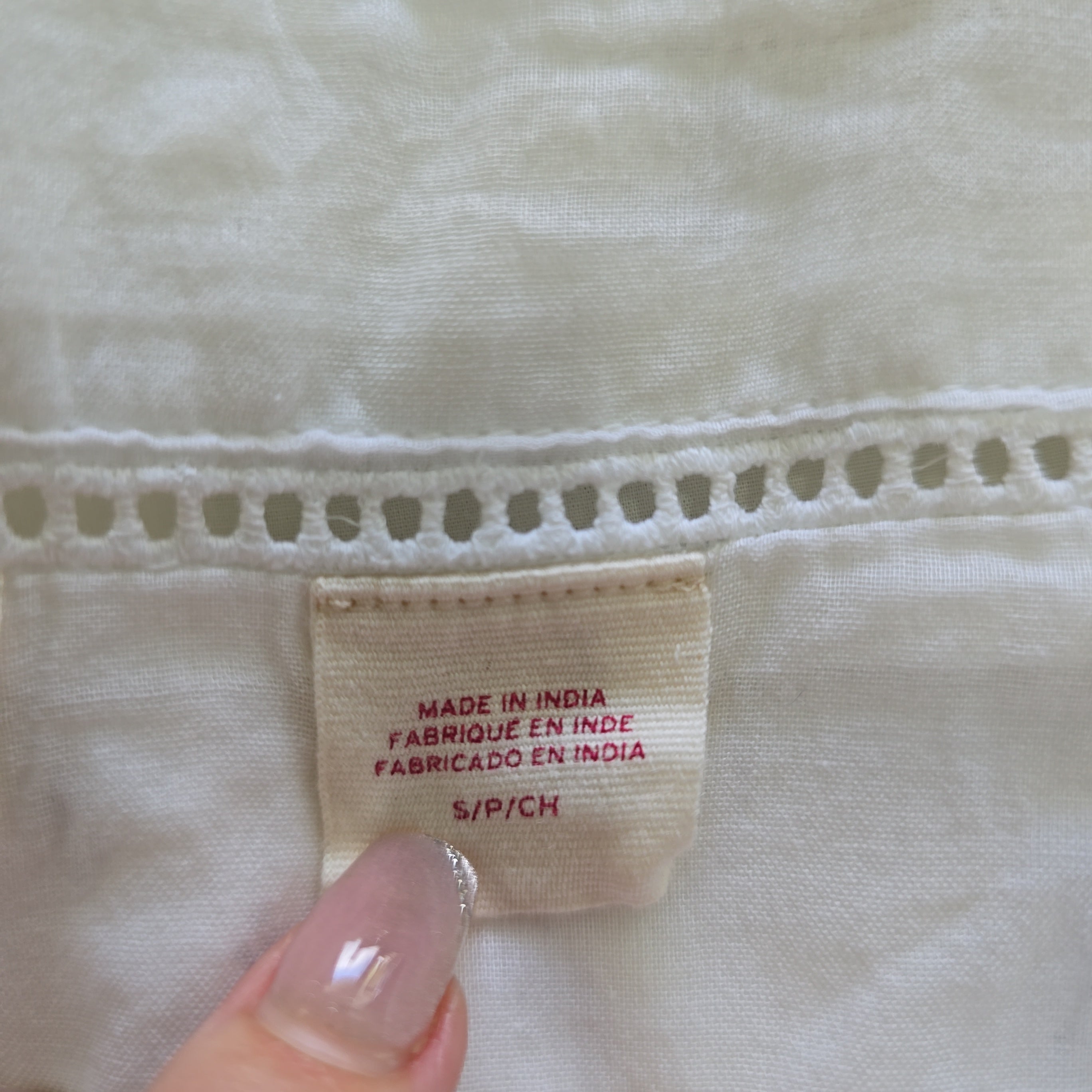 Close-up of a fabric tag on a light-colored garment with visible text.