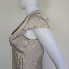 Mannequin wearing a beige top with a plain background