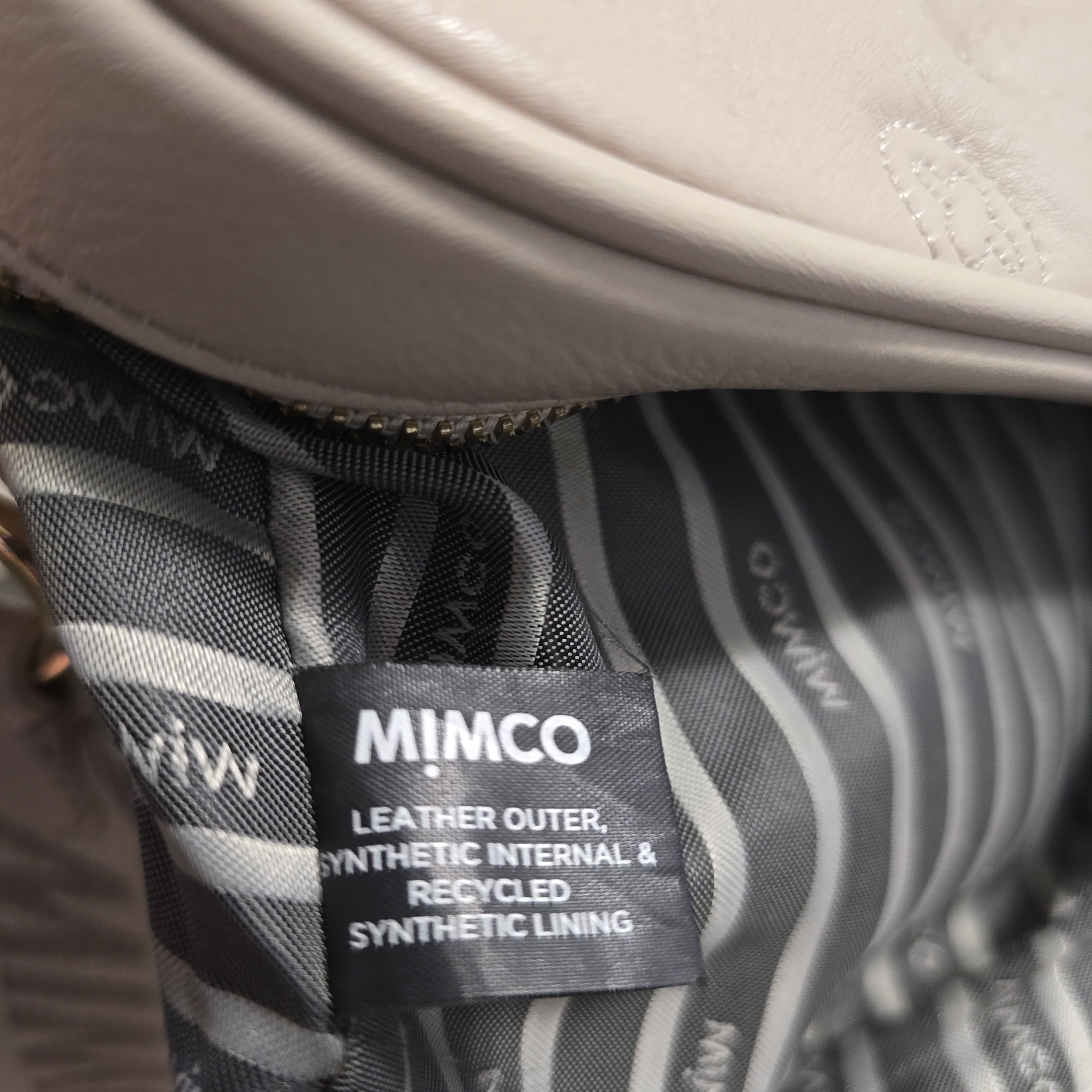 Close-up of a Mimco product with a label on a striped background