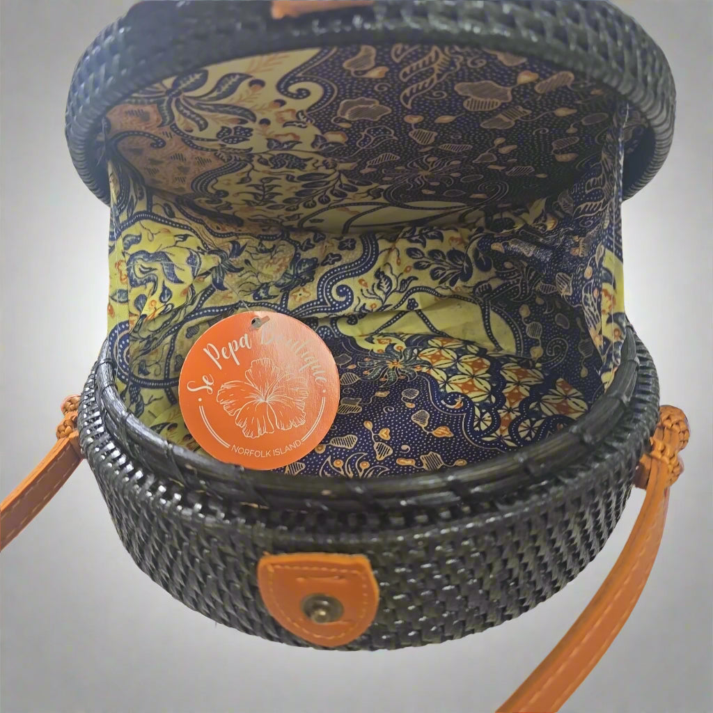 Decorative woven basket with floral pattern and orange tag on a tiled floor.