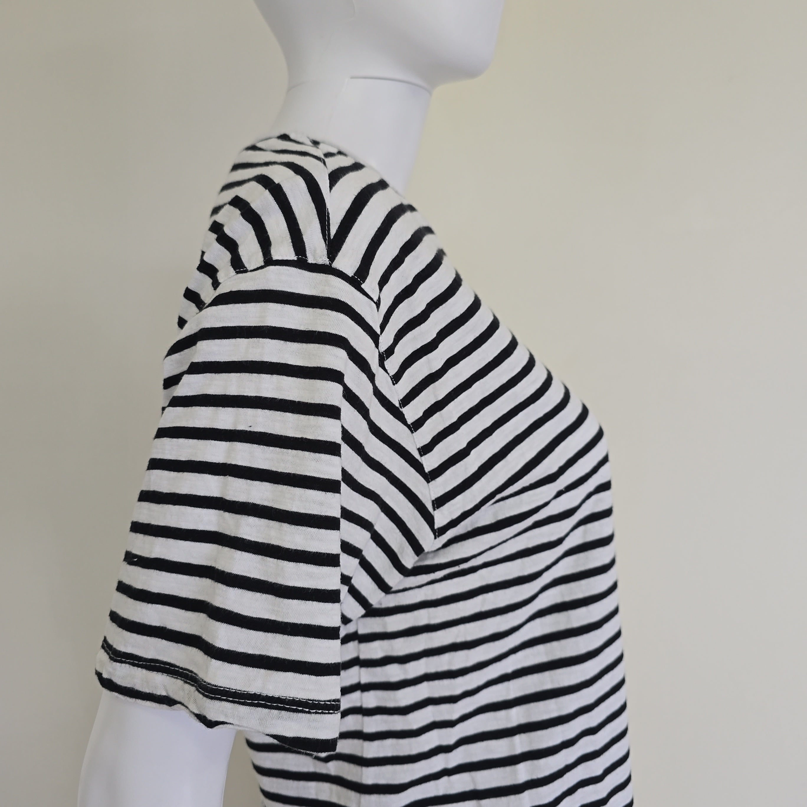 Mannequin wearing a black and white striped garment on a plain background
