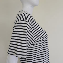 Mannequin wearing a black and white striped garment on a plain background