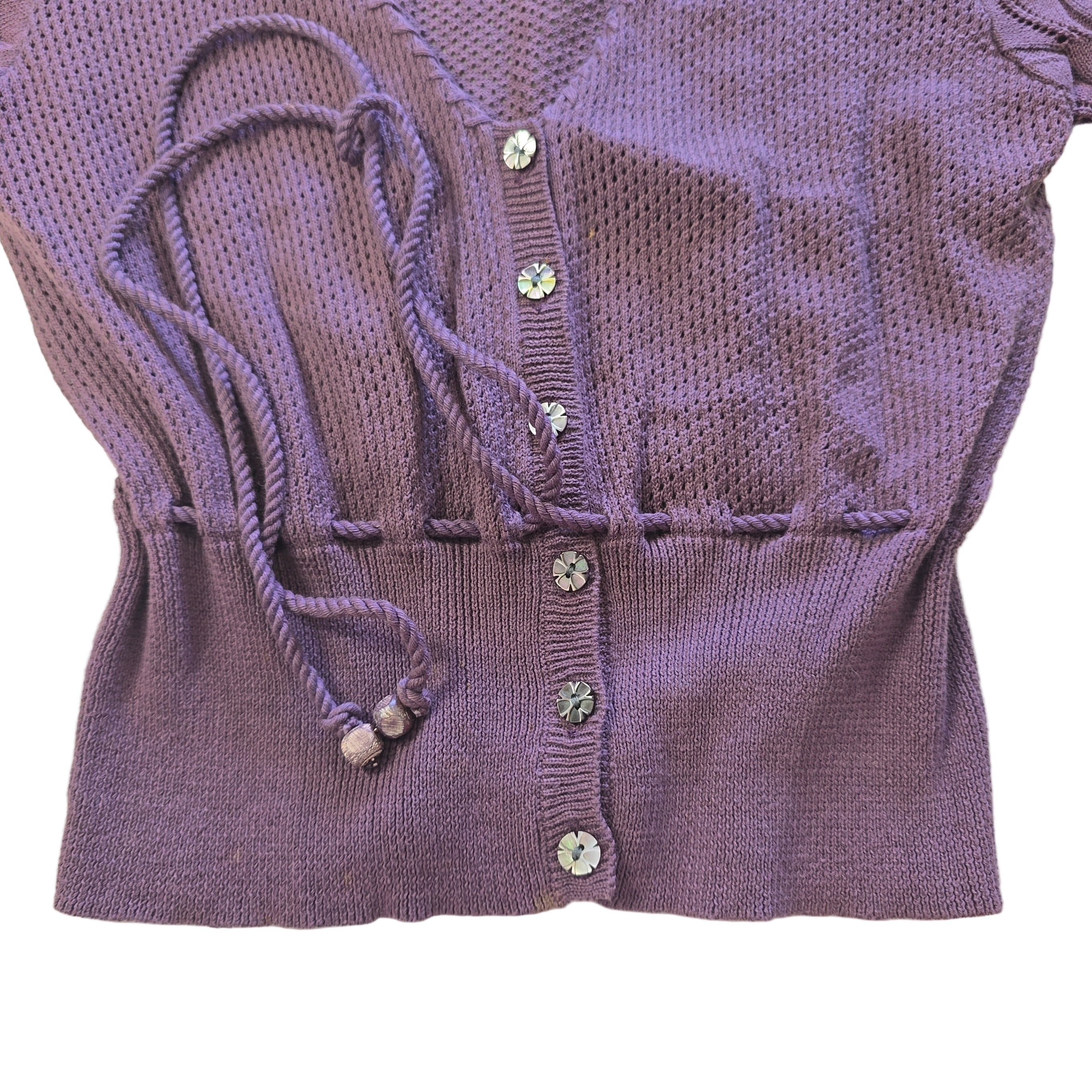 Purple knitted cardigan with tassels and decorative buttons on a light background