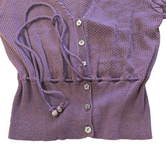 Purple knitted cardigan with tassels and decorative buttons on a light background