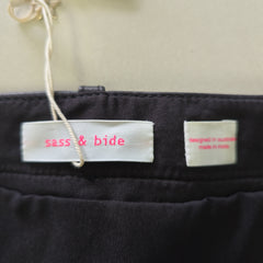 Black fabric with 'sass & bide' labels on a beige background
