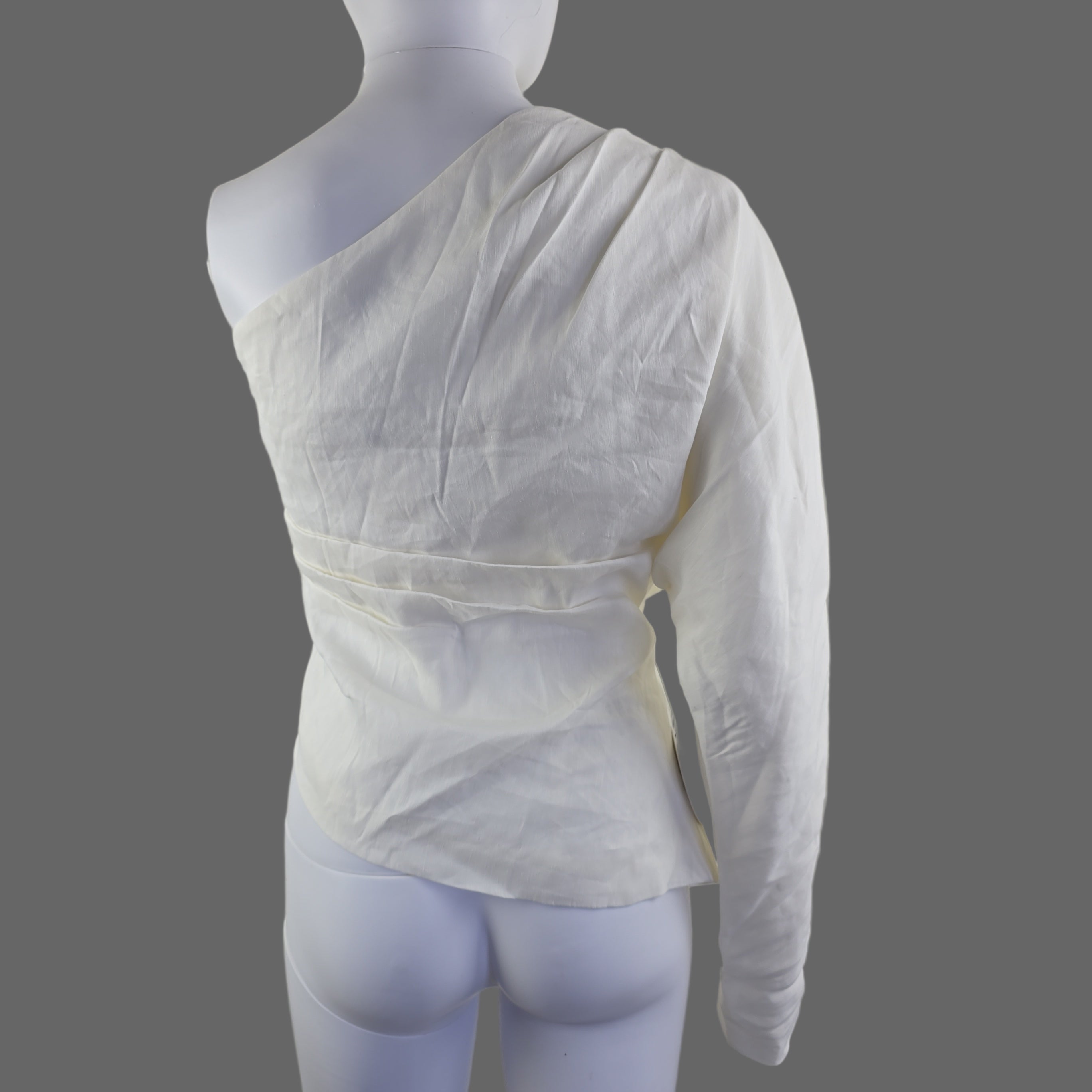 White top on a mannequin arm against a plain background