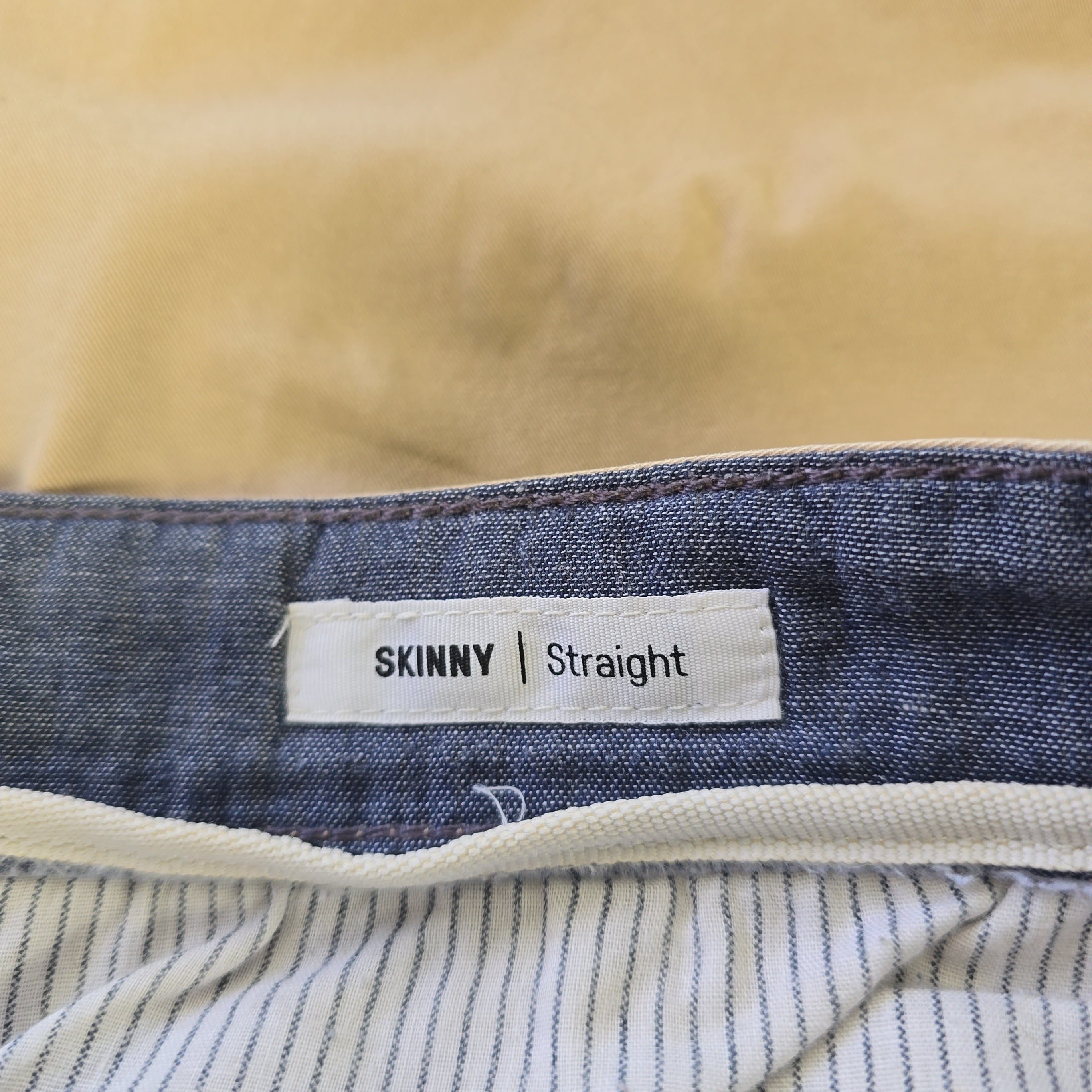 Close-up of a denim fabric with a 'Skinny' label on a beige background