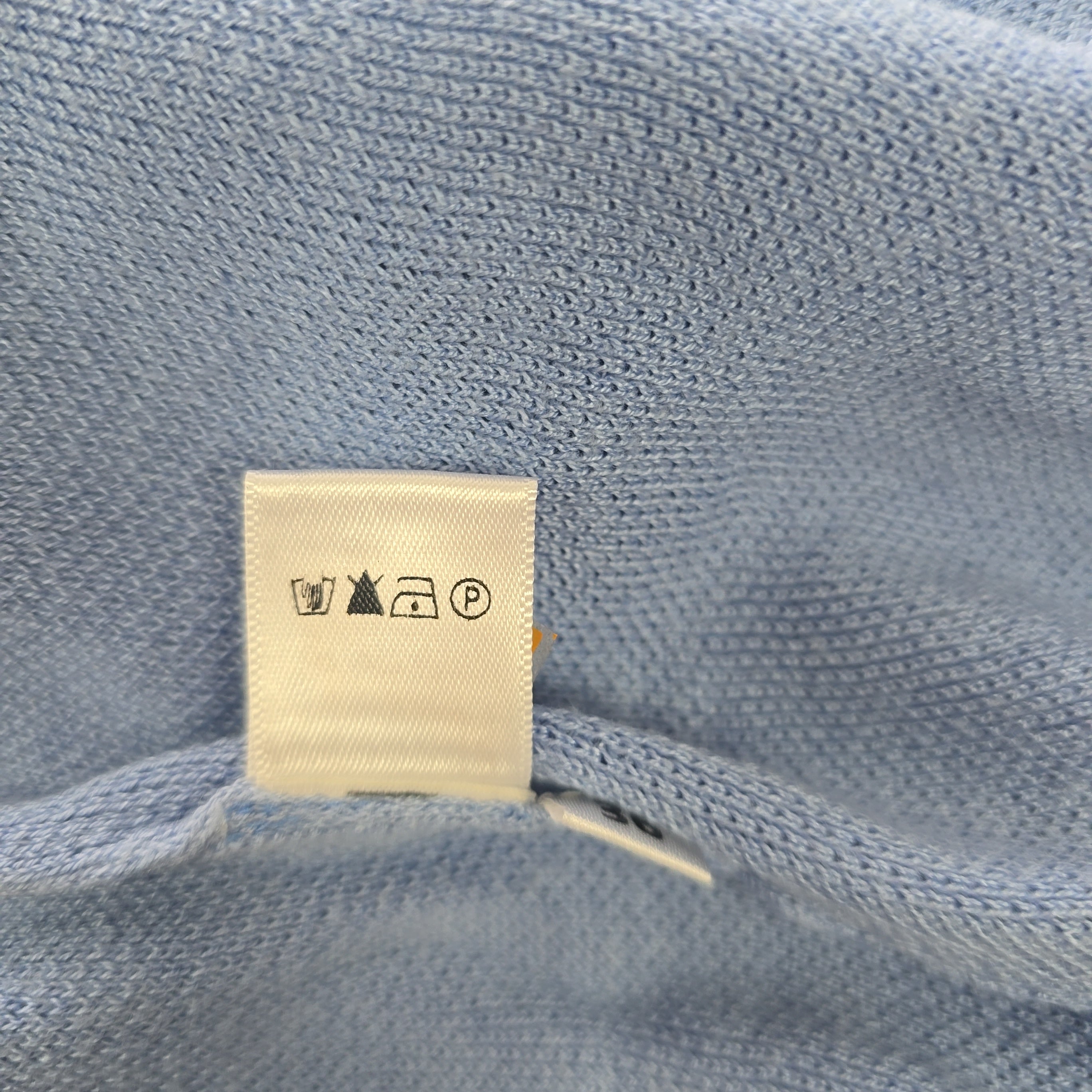 Close-up of a blue knitted garment with a label on it.