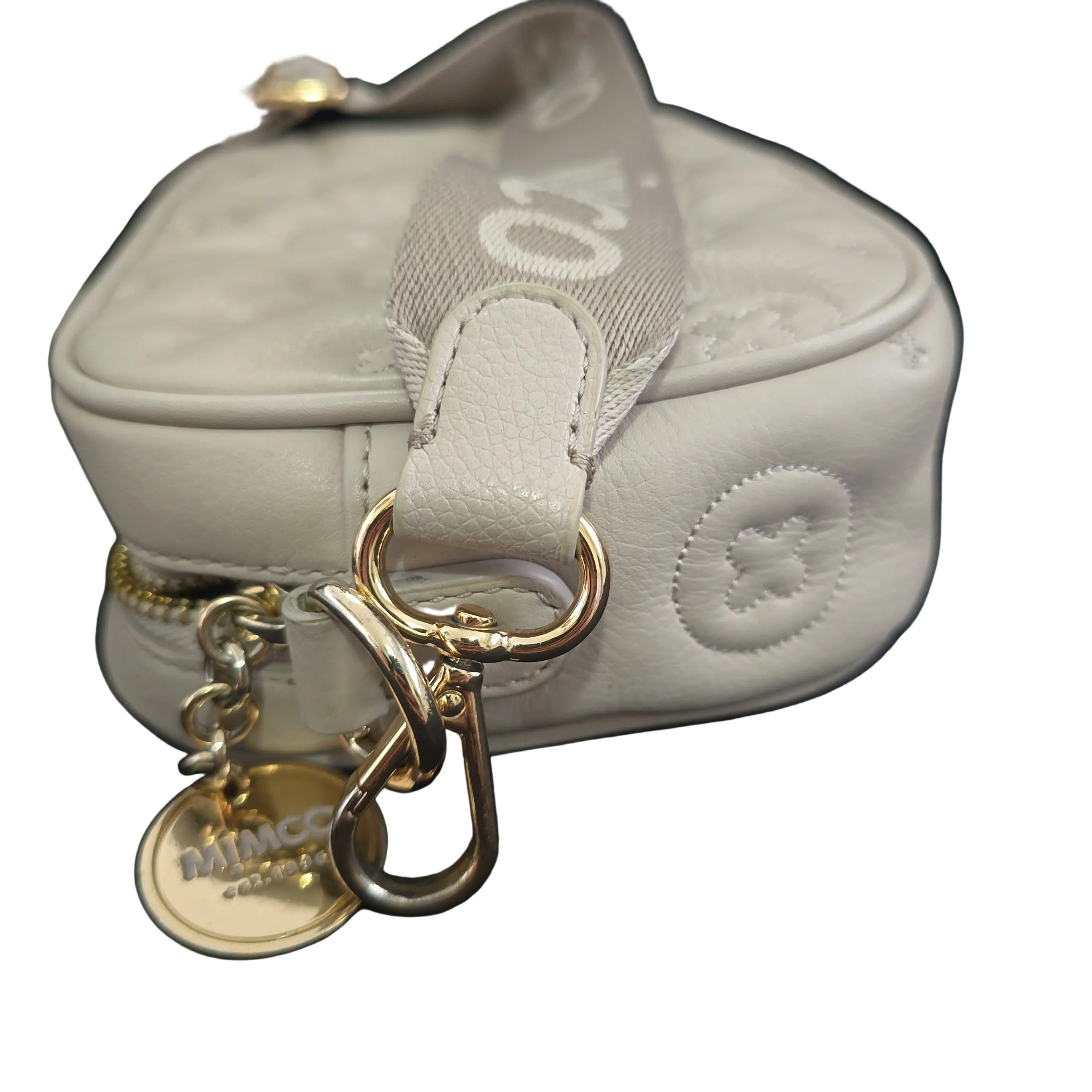 Close-up of a light gray handbag with gold keychain and tag on a light background
