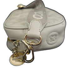 Close-up of a light gray handbag with gold keychain and tag on a light background