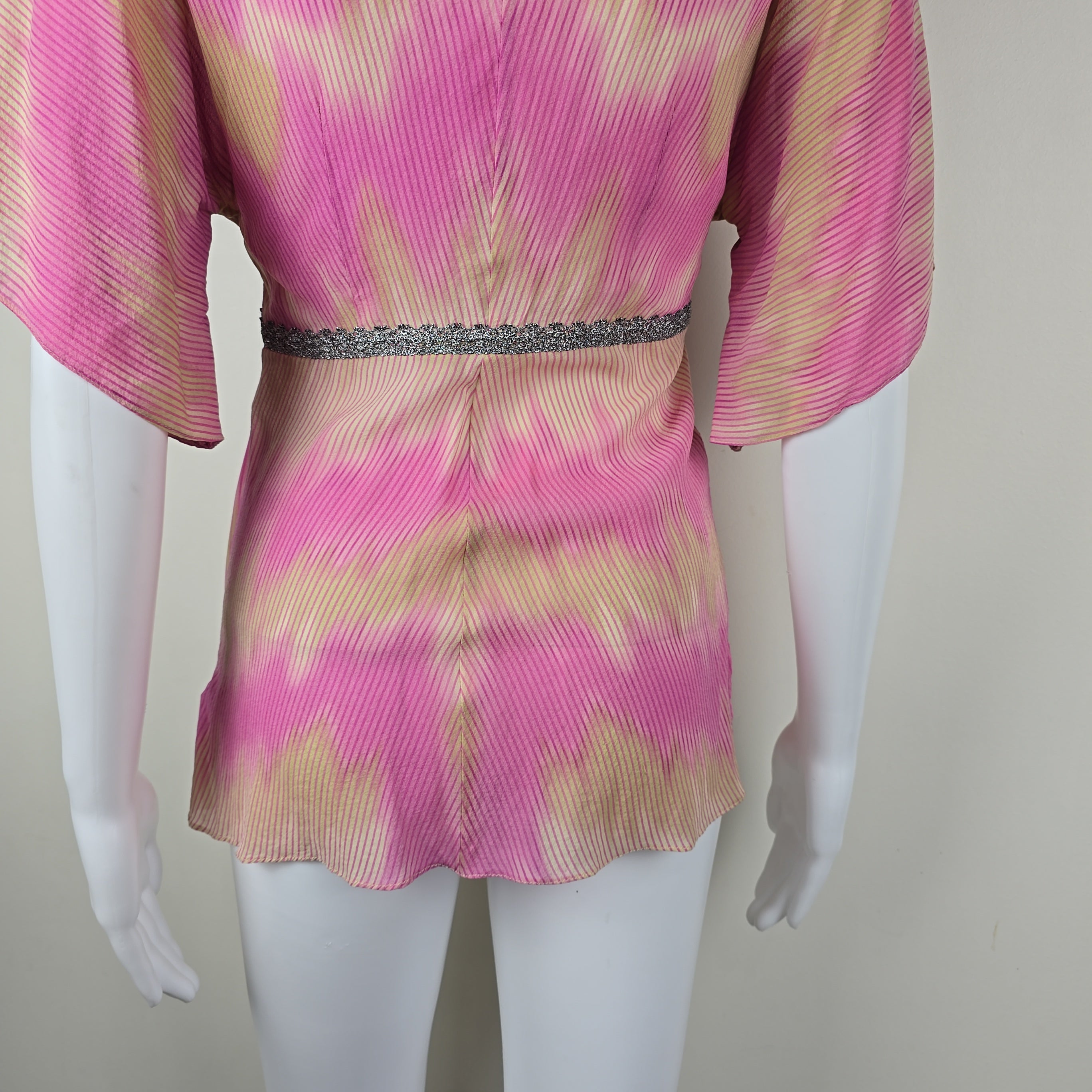 Mannequin wearing a pink and gold patterned garment on a plain background