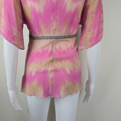 Mannequin wearing a pink and gold patterned garment on a plain background