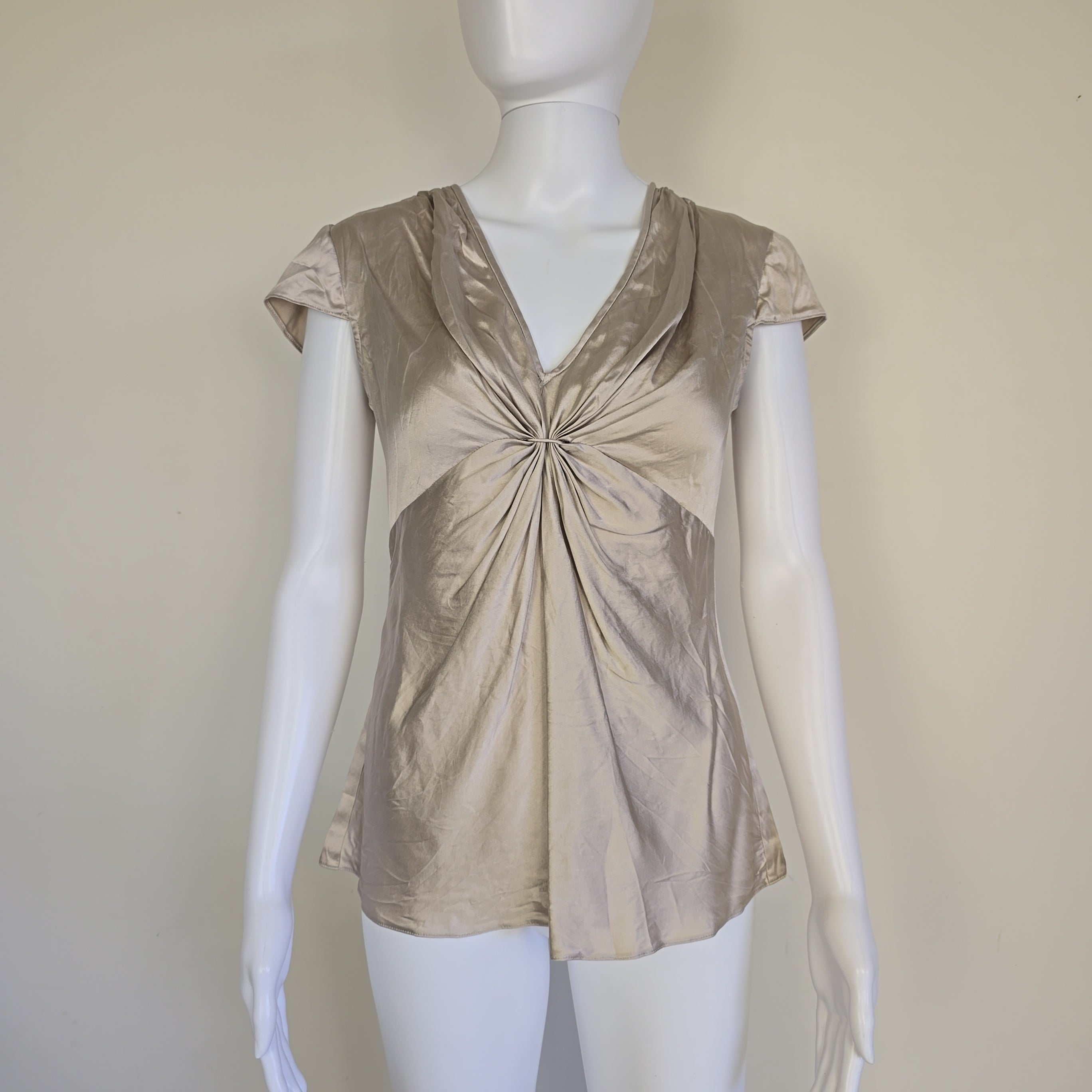 Beige top on a mannequin against a plain background