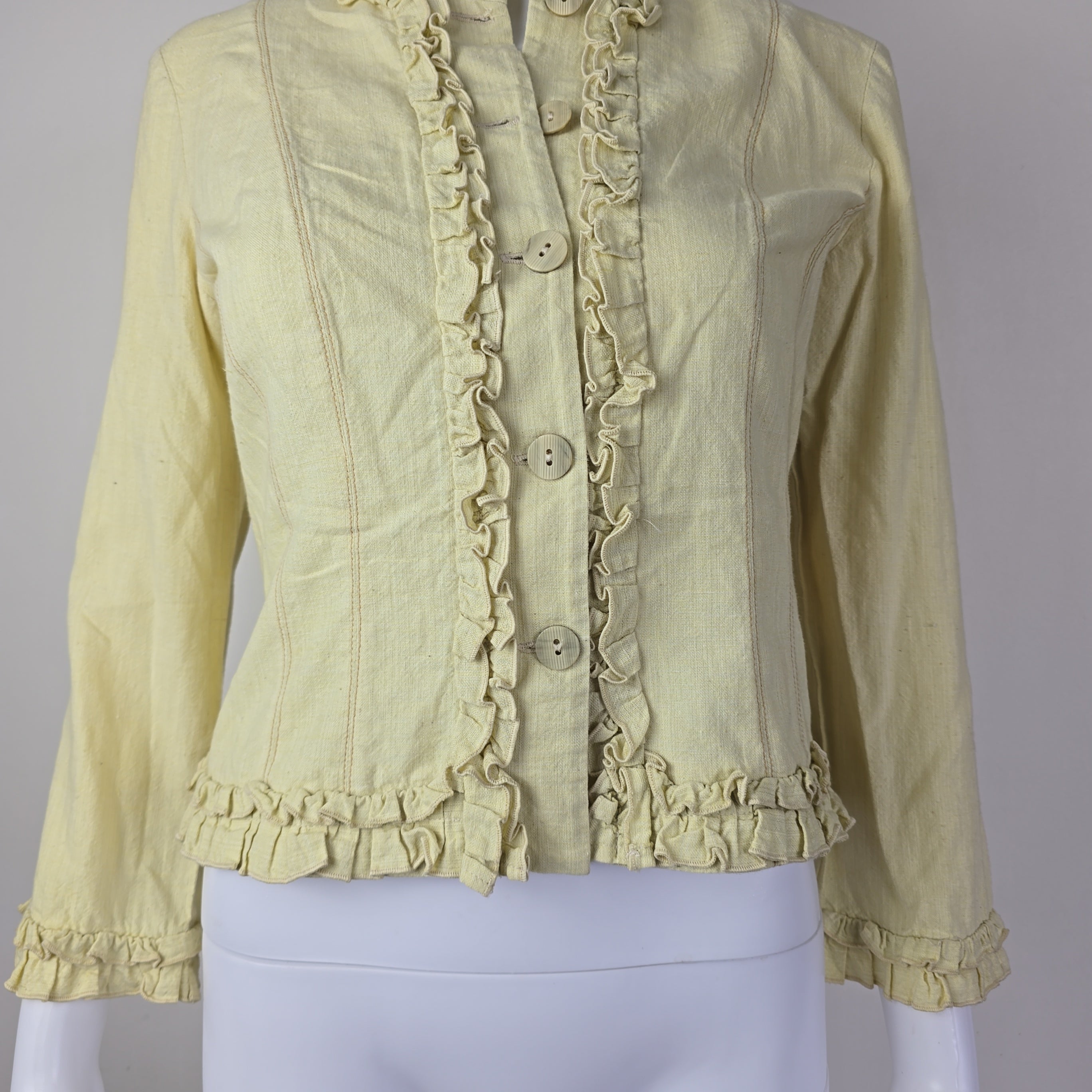 Light yellow jacket with frill details on a light background