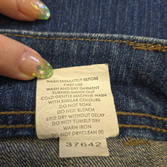 Close-up of a clothing label on denim fabric with a hand holding it.