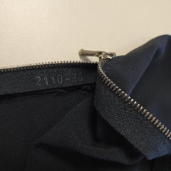 Close-up of a black pant leg with a zipper on a beige background