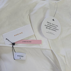 Sheike clothing tags on a white garment with a pink tag.