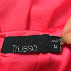 Black tag with 'Truese' branding on a red fabric background
