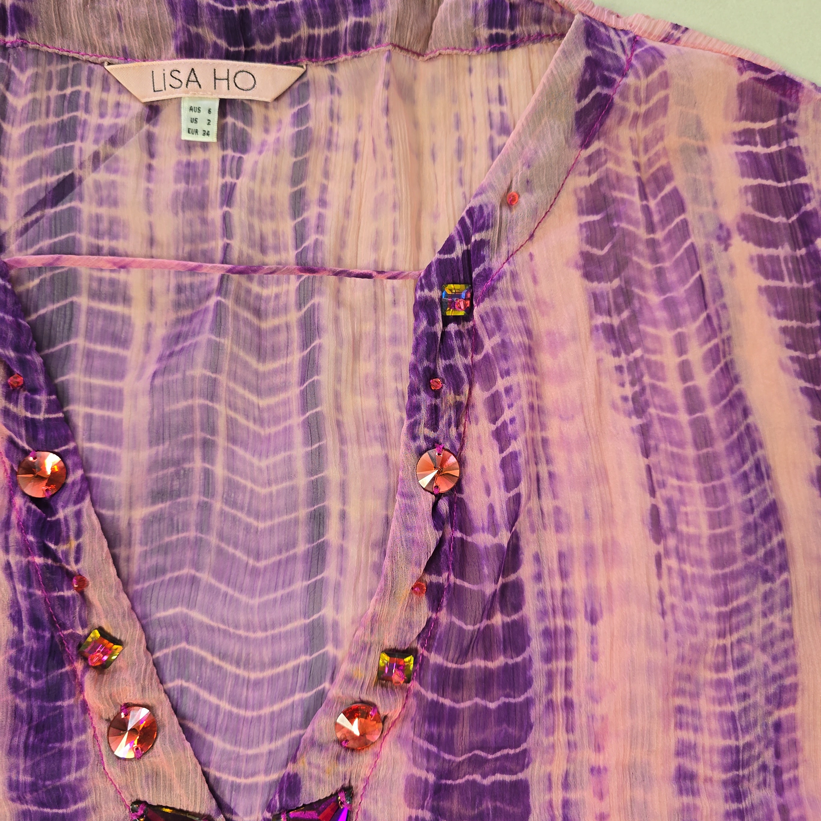 Purple and pink patterned fabric with embellishments and a visible brand tag.