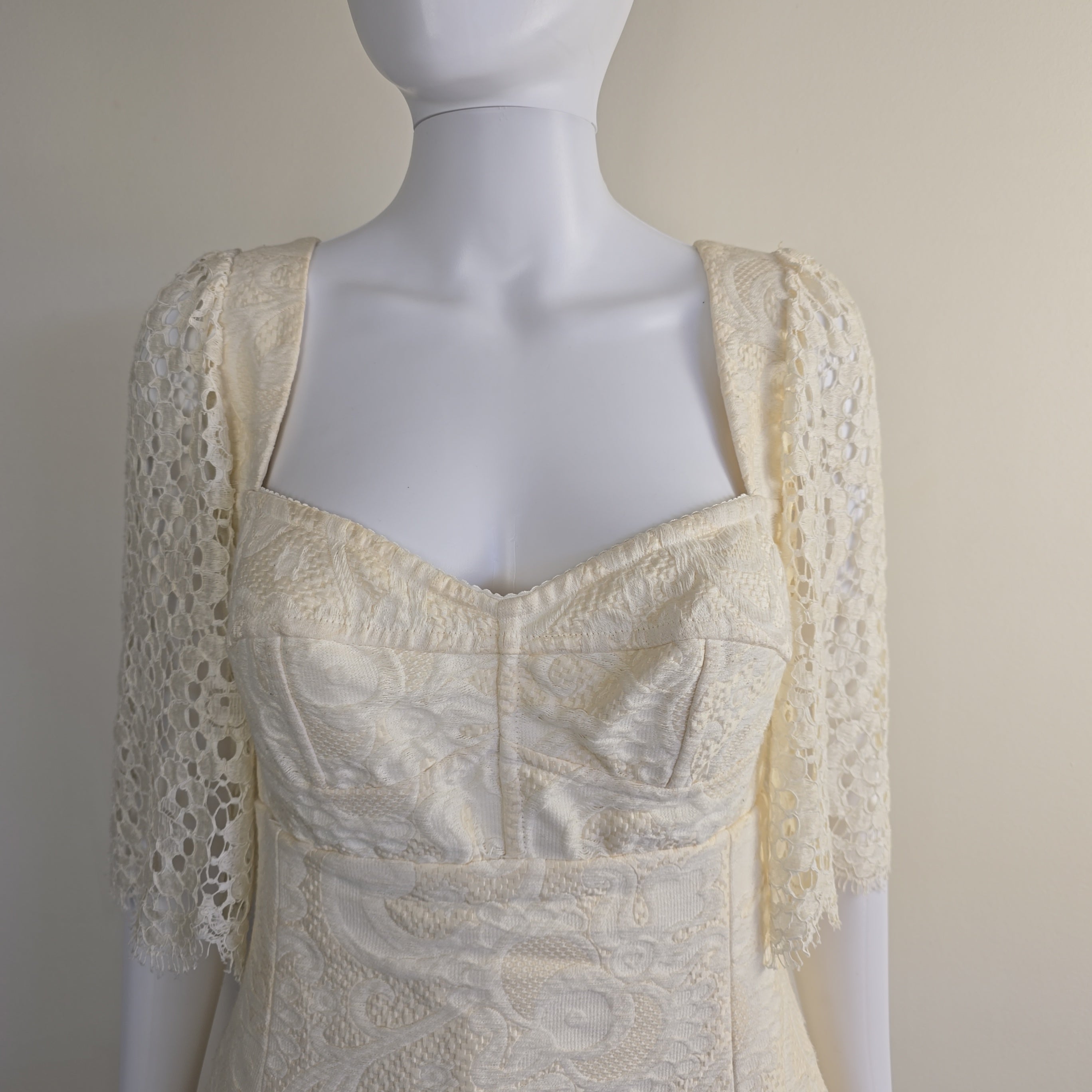 Mannequin wearing a cream-colored lace garment against a neutral background