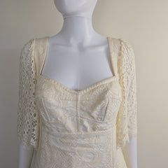 Mannequin wearing a cream-colored lace garment against a neutral background