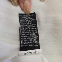 Clothing label on a white garment with text and numbers.