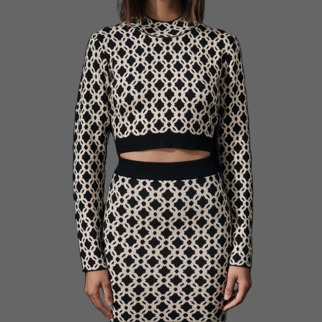 Model wearing a black and white patterned outfit with sunglasses on a plain background