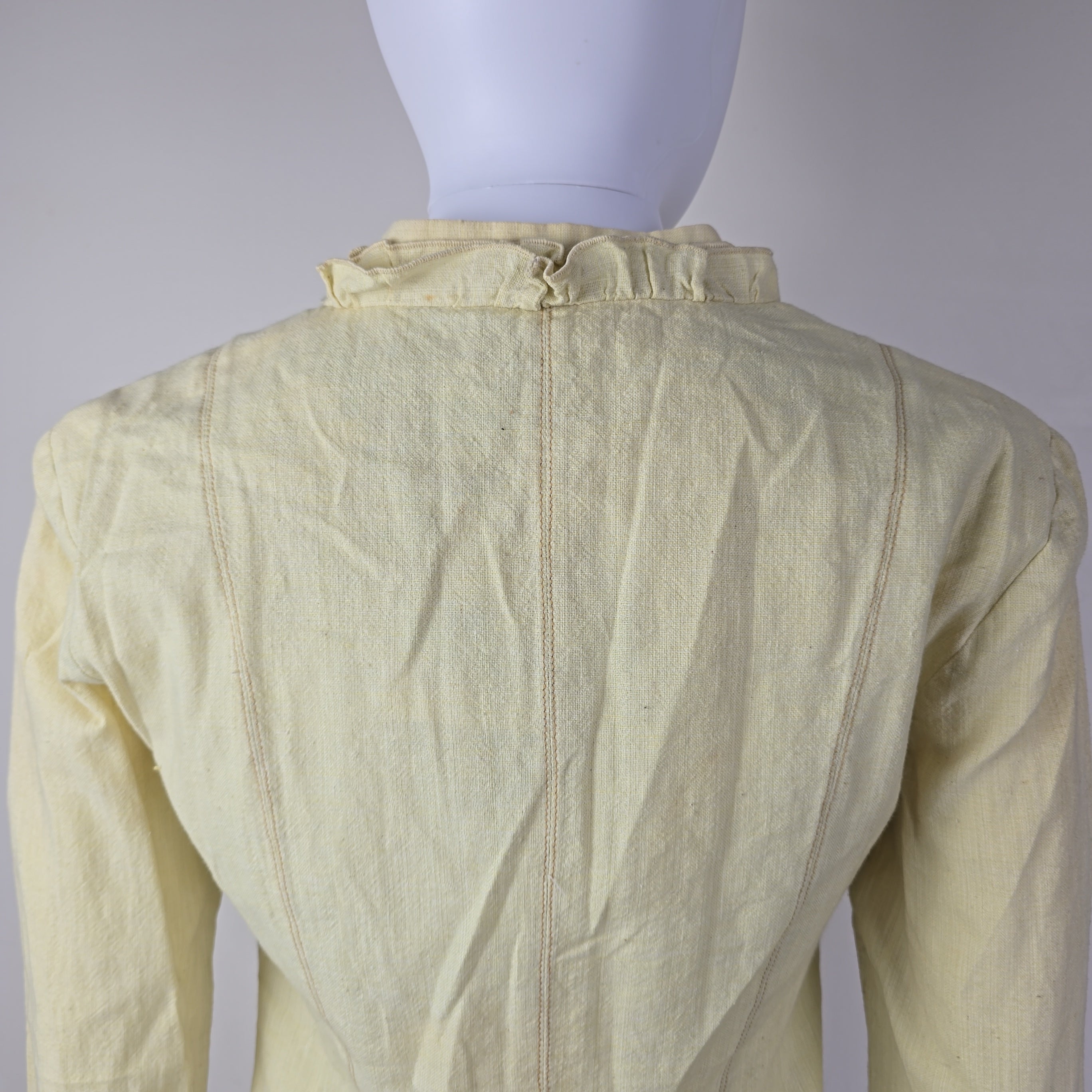 Light yellow jacket with frill details on a light background