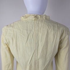 Light yellow jacket with frill details on a light background