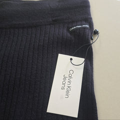 Black ribbed knit garment with a Calvin Klein Jeans tag on a beige background
