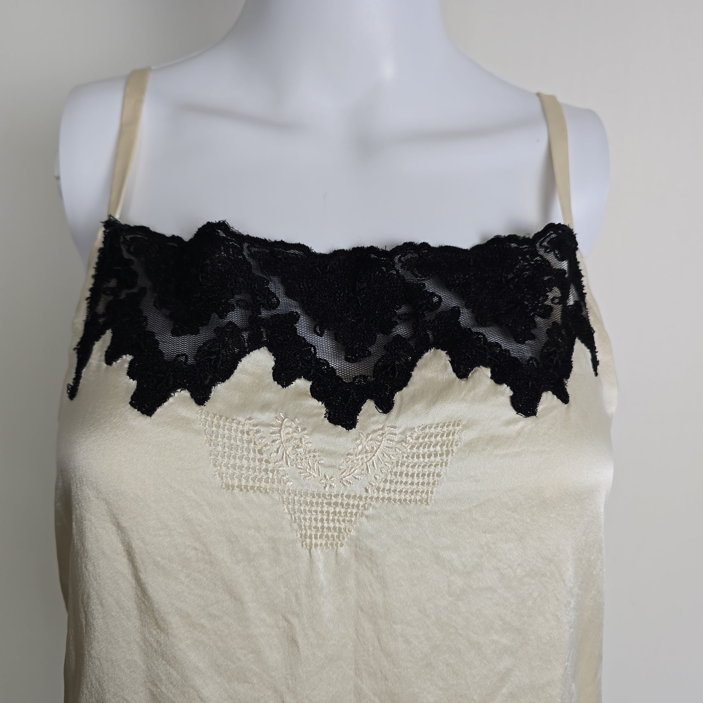 White lace garment on a mannequin with black lace trim against a plain background