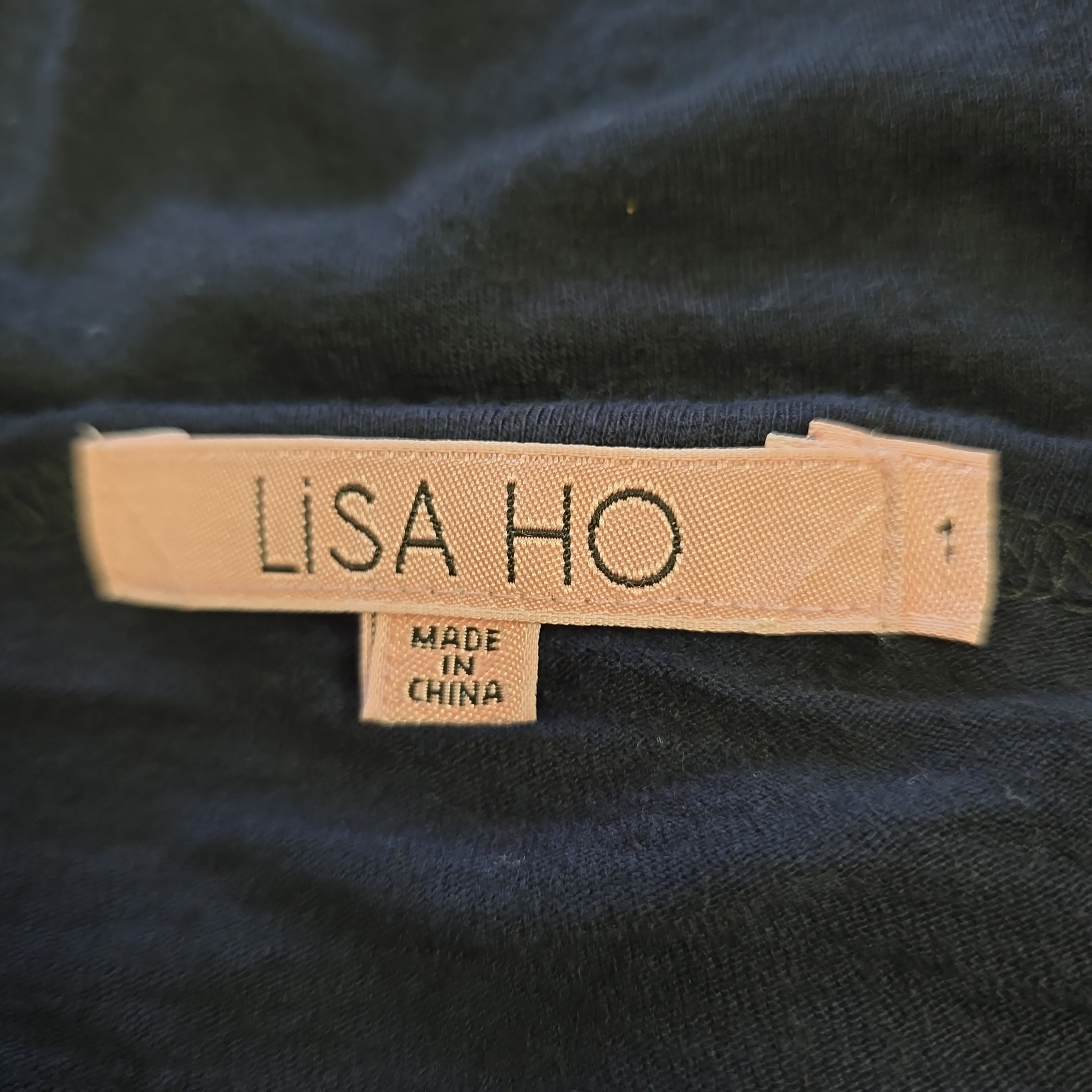 Close-up of a 'LISA HO' label on dark fabric