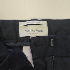 Close-up of a black Pants with a Veronika Maine label on a beige background