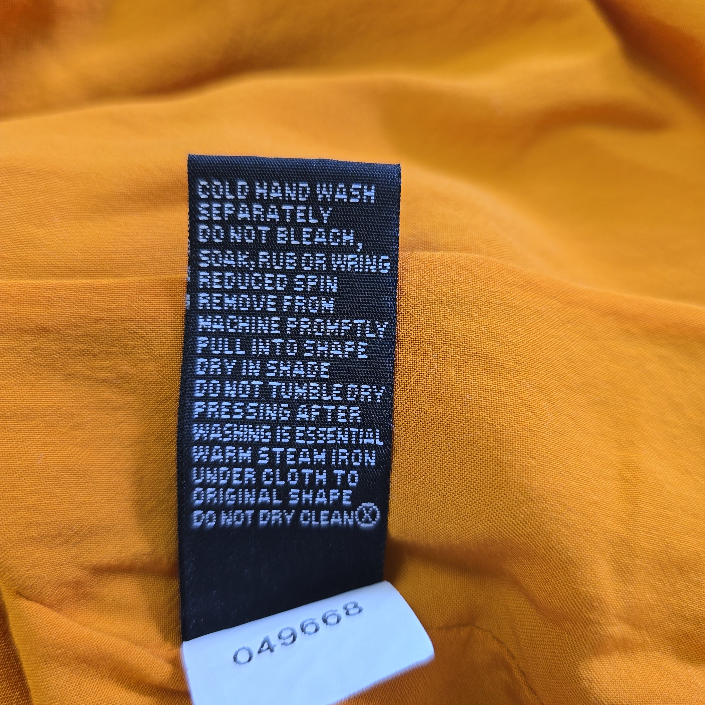 Clothing label on a mustard yellow fabric background